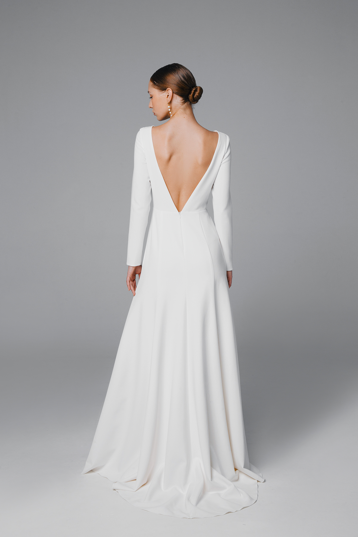 Fit and flare wedding dress with low back and long sleeves.