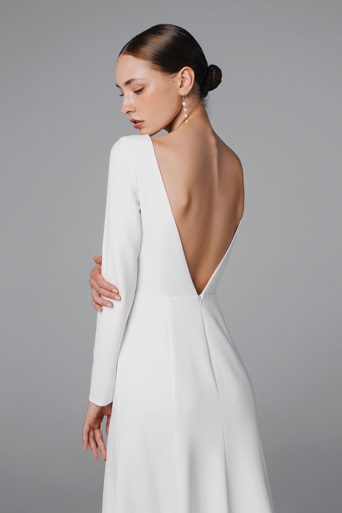 Fit and flare wedding dress with low back and long sleeves.