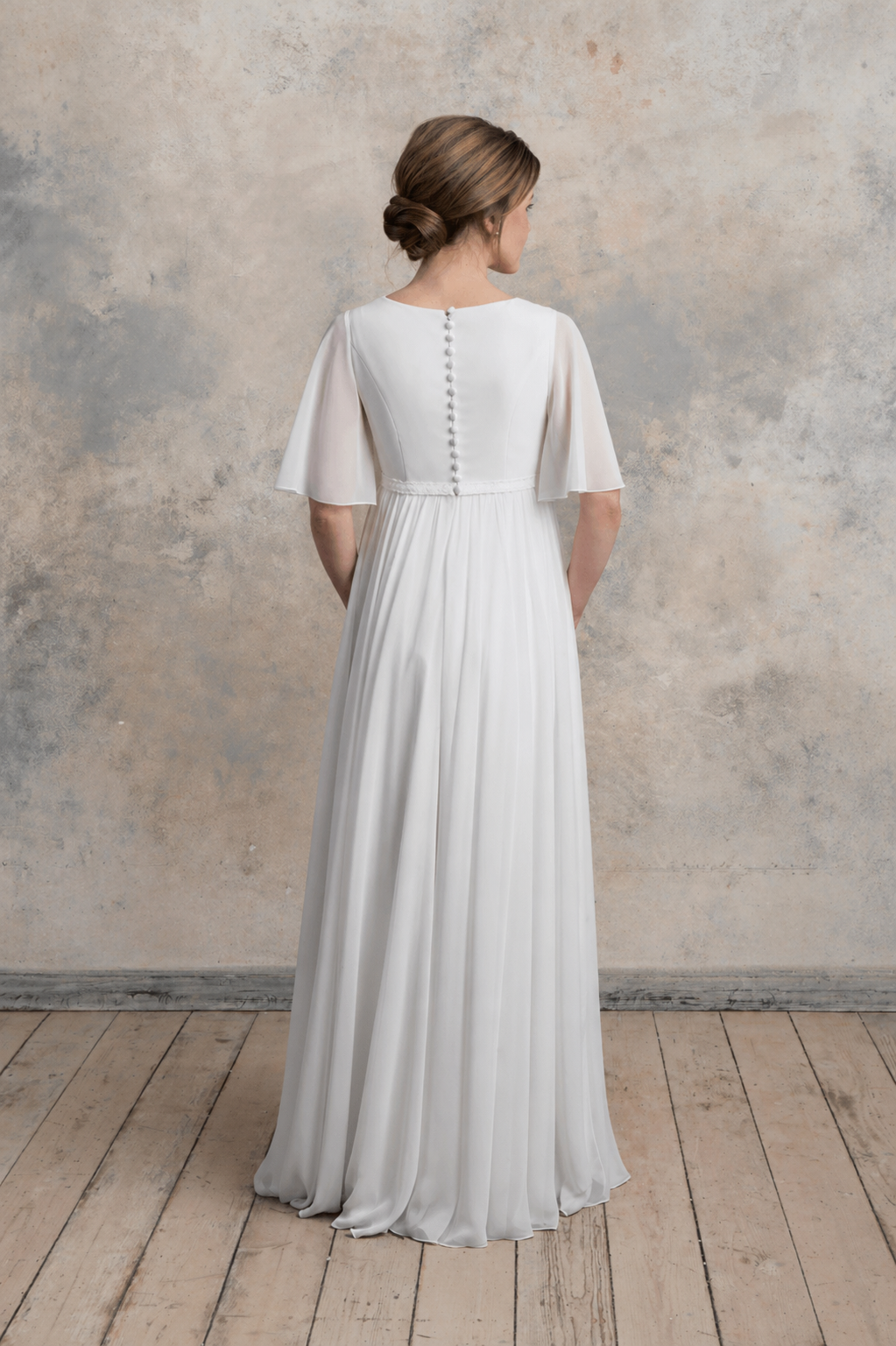 Back view of a maternity chiffon gown with flutter sleeves and covered buttons.