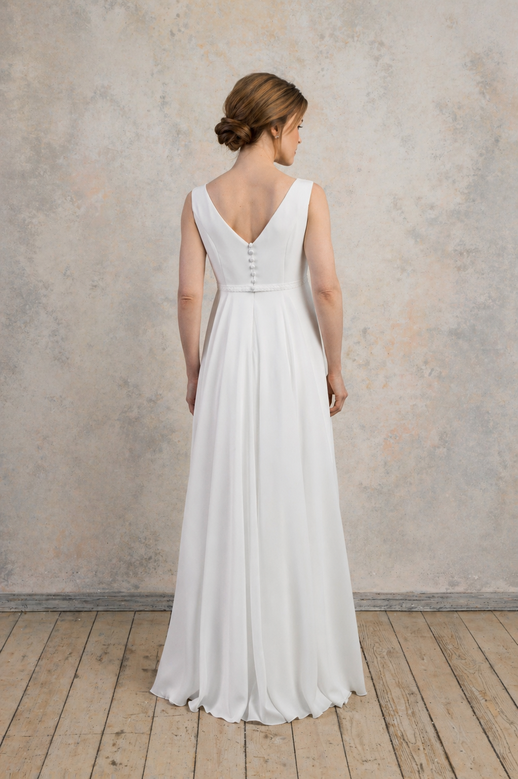 Full back view of a maternity crepe chiffon gown with a V-back and flowing A-line skirt.