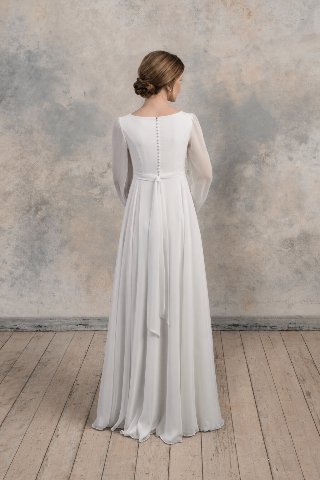 Back view of a maternity chiffon gown with long sheer sleeves and covered buttons.