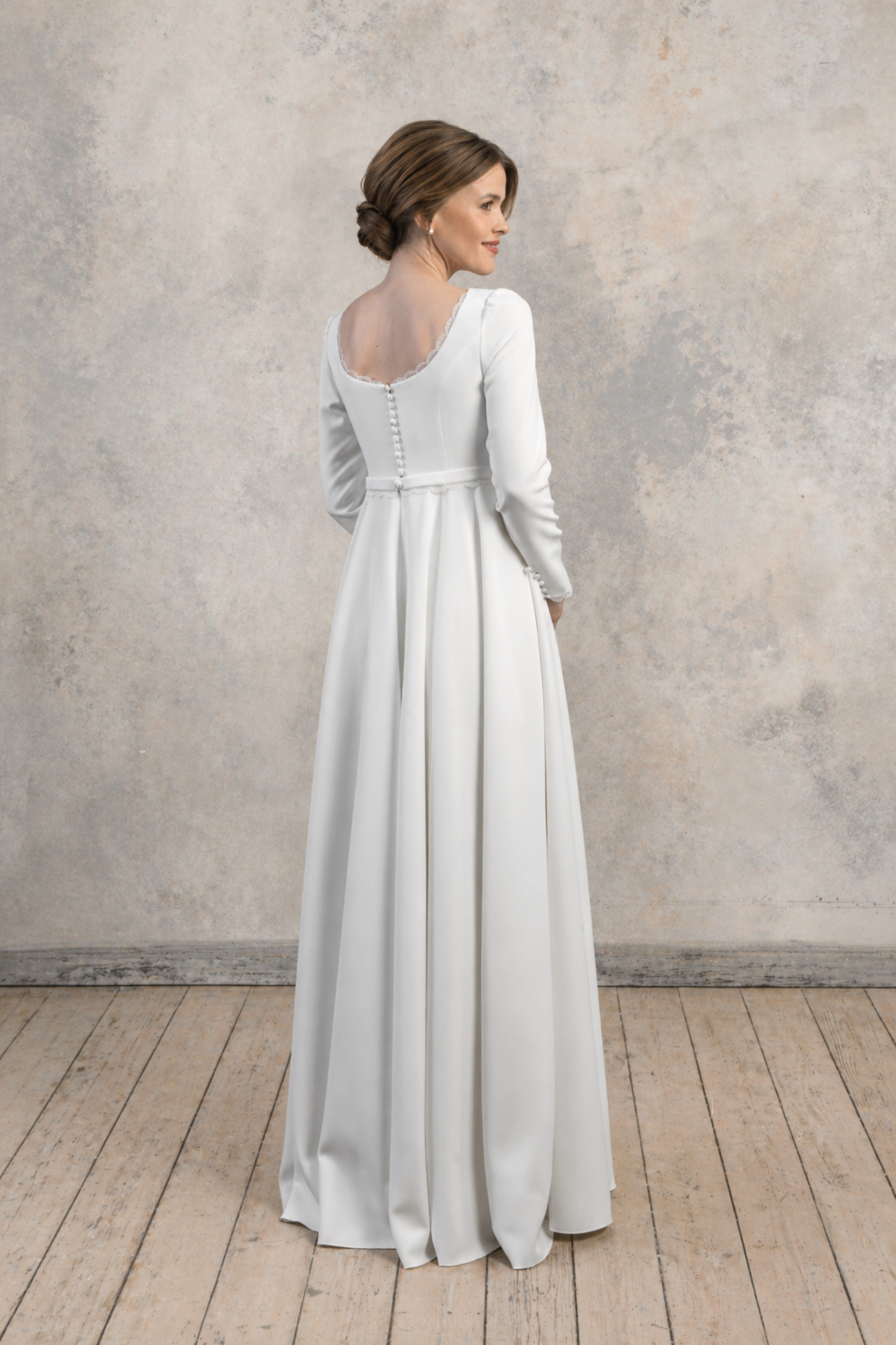 Side-back view of a long-sleeve maternity gown with a structured bodice and flowing skirt.