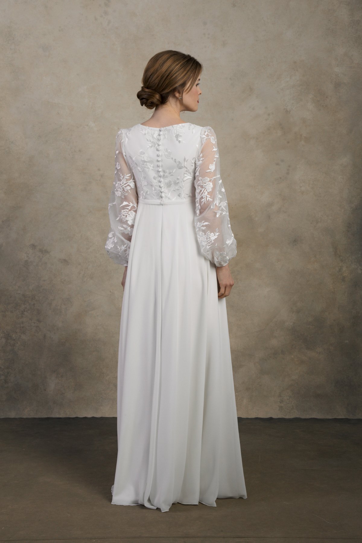 Back view of a maternity gown with lace sleeves and embroidered detailing.