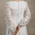 Close-up of a maternity gown with an embroidered bodice, lace sleeves, and covered buttons.
