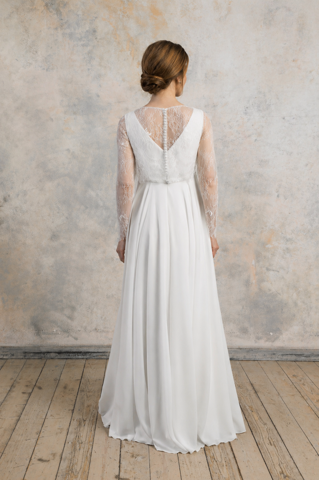 Back view of a maternity gown with lace sleeves, illusion back, and a flowing chiffon skirt.