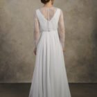 Back view of a maternity gown with lace sleeves, illusion back, and a flowing chiffon skirt.