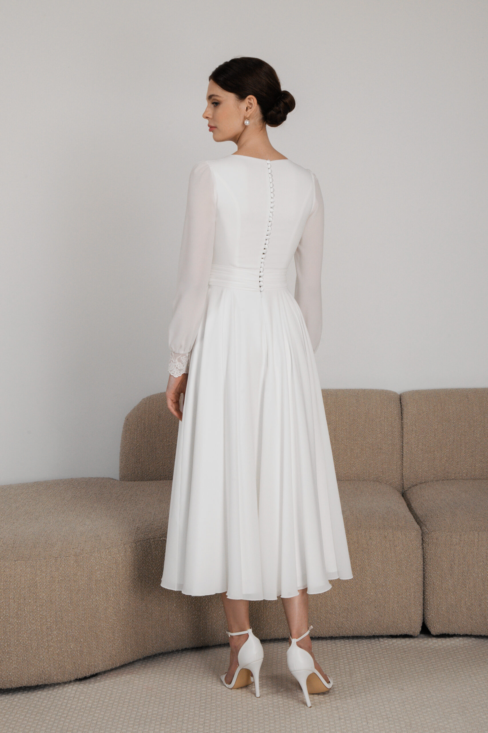 Back view of chiffon wedding gown with sheer sleeves and tea-length hem
