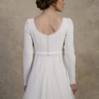 Close-up back view of a long-sleeve maternity gown with a deep scoop back and covered buttons.