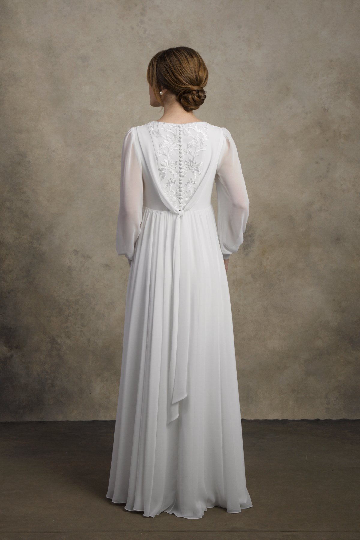 Full back view of a maternity chiffon gown with embroidered detail and long sleeves.