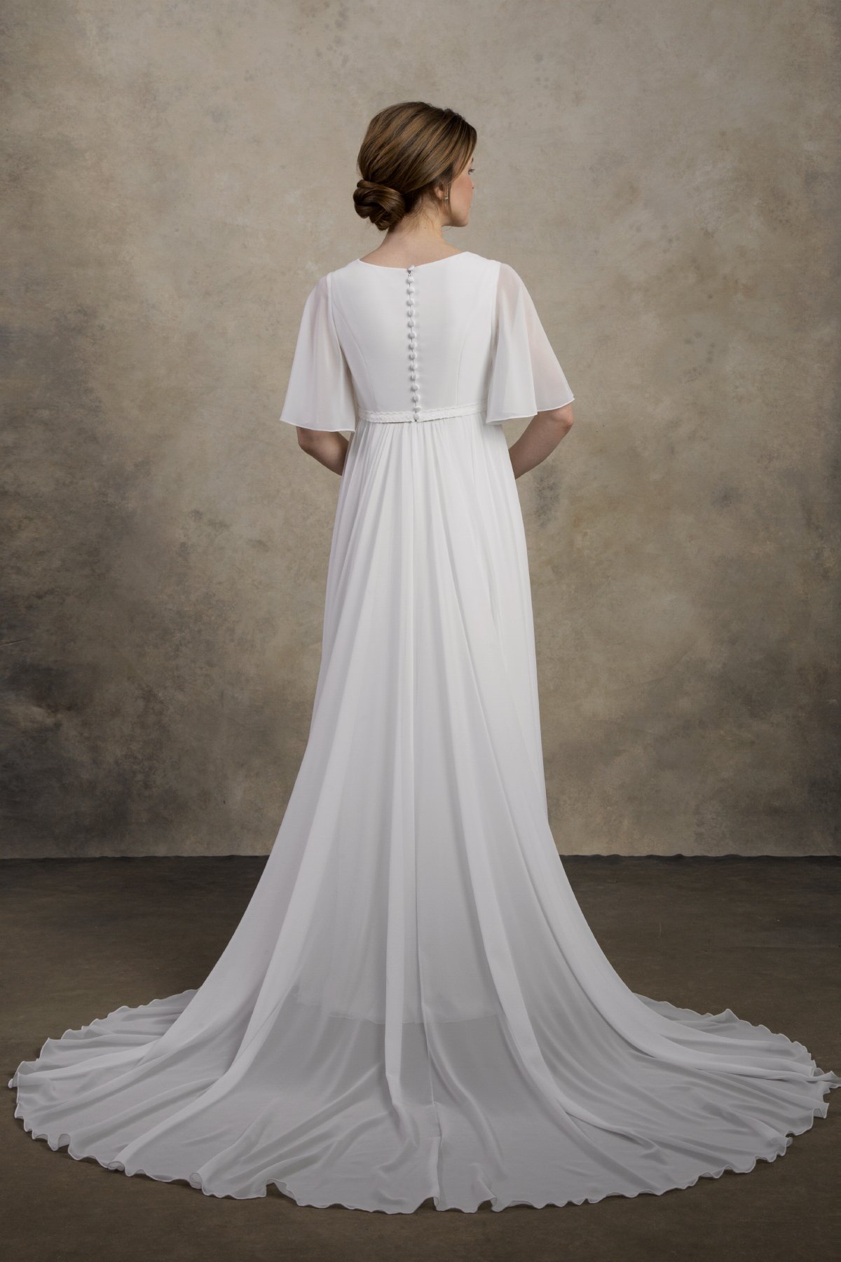 Full back view of a maternity chiffon gown with flutter sleeves and a long flowing train.