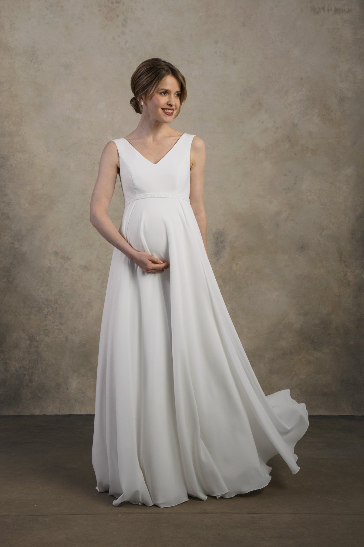 Front view of a maternity gown with a V-neckline and flowing chiffon skirt.
