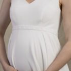 Close-up of a maternity gown with a V-neckline and softly gathered empire waist.