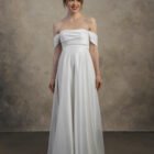 Front view of an off-the-shoulder maternity gown with a draped bodice and long flowing skirt.