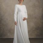 Front view of a long-sleeve maternity gown with a smooth bodice and soft A-line skirt.