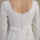 Close-up back view of a long-sleeve maternity gown with a deep scoop back and covered buttons.