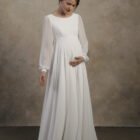 Maternity gown with long sleeves, an empire waist, and a flowing A-line skirt.