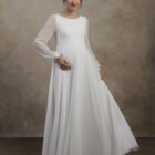 Maternity gown with long sleeves, a softly draped skirt, and a clean, minimal design.