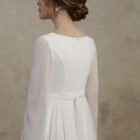 Maternity gown with sheer long sleeves, a clean back, and a softly defined waistline.