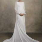 Maternity gown with long sheer sleeves, an empire waist, and a flowing skirt with soft movement.