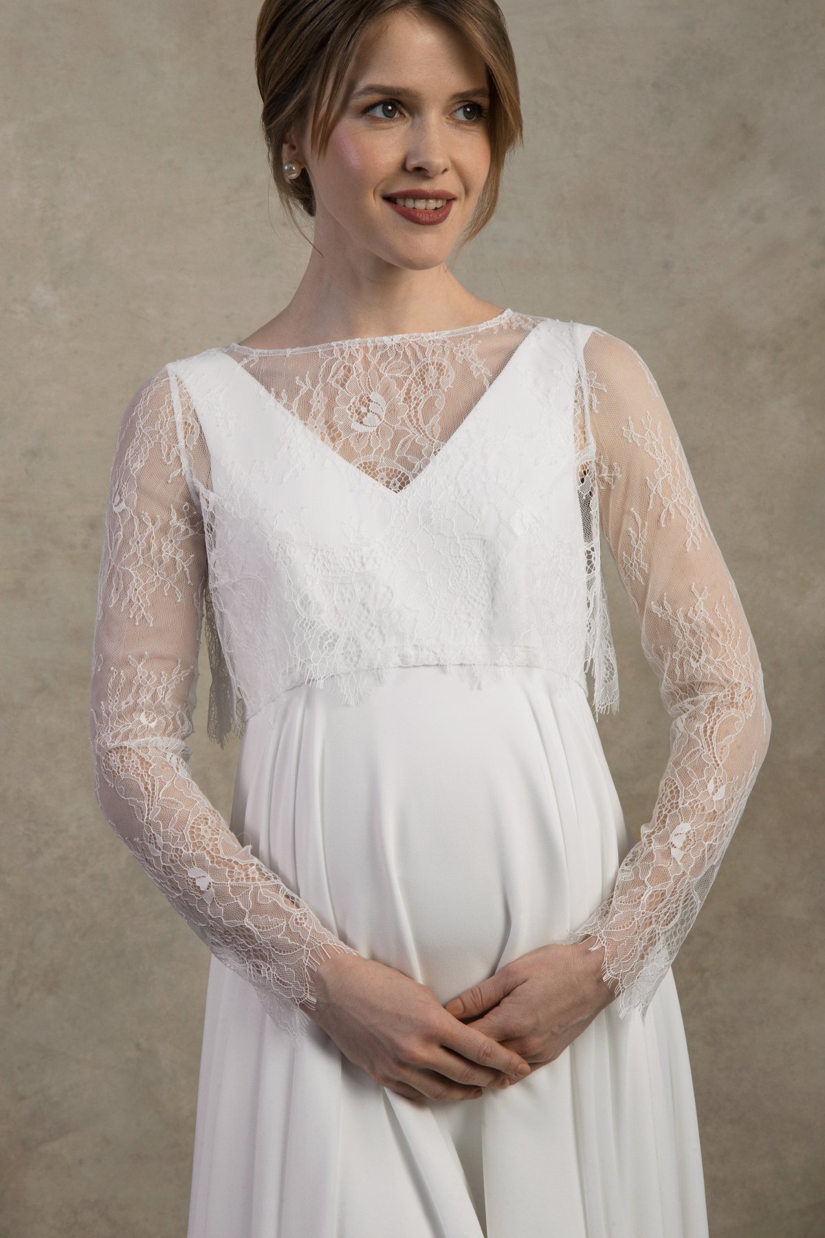 Close-up of a maternity gown with sheer lace sleeves and layered V-neck detailing.