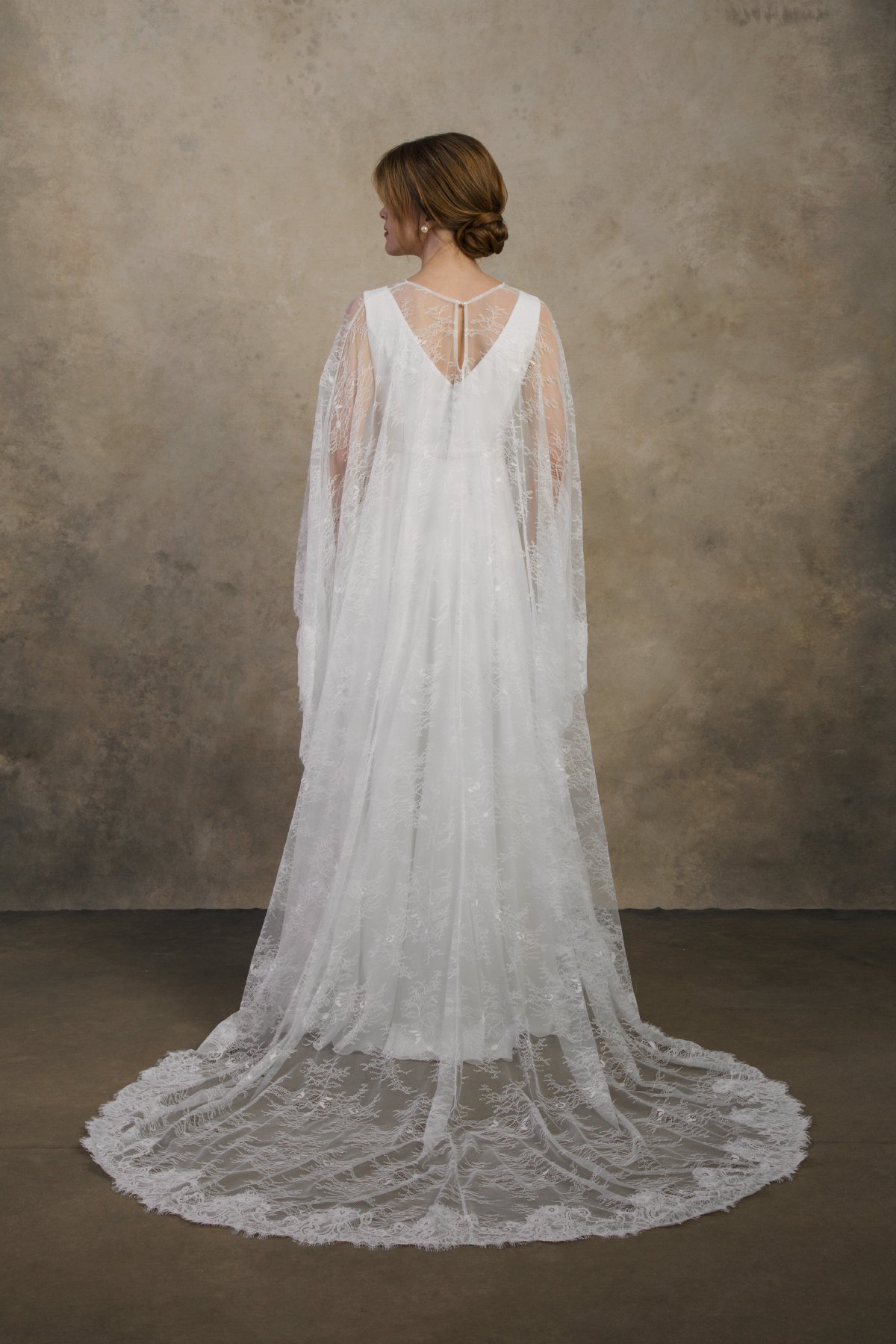 Back view of a maternity gown with a lace cape, long train, and V-back.