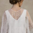 Close-up of a maternity gown with a sheer lace back detail and chiffon cape.