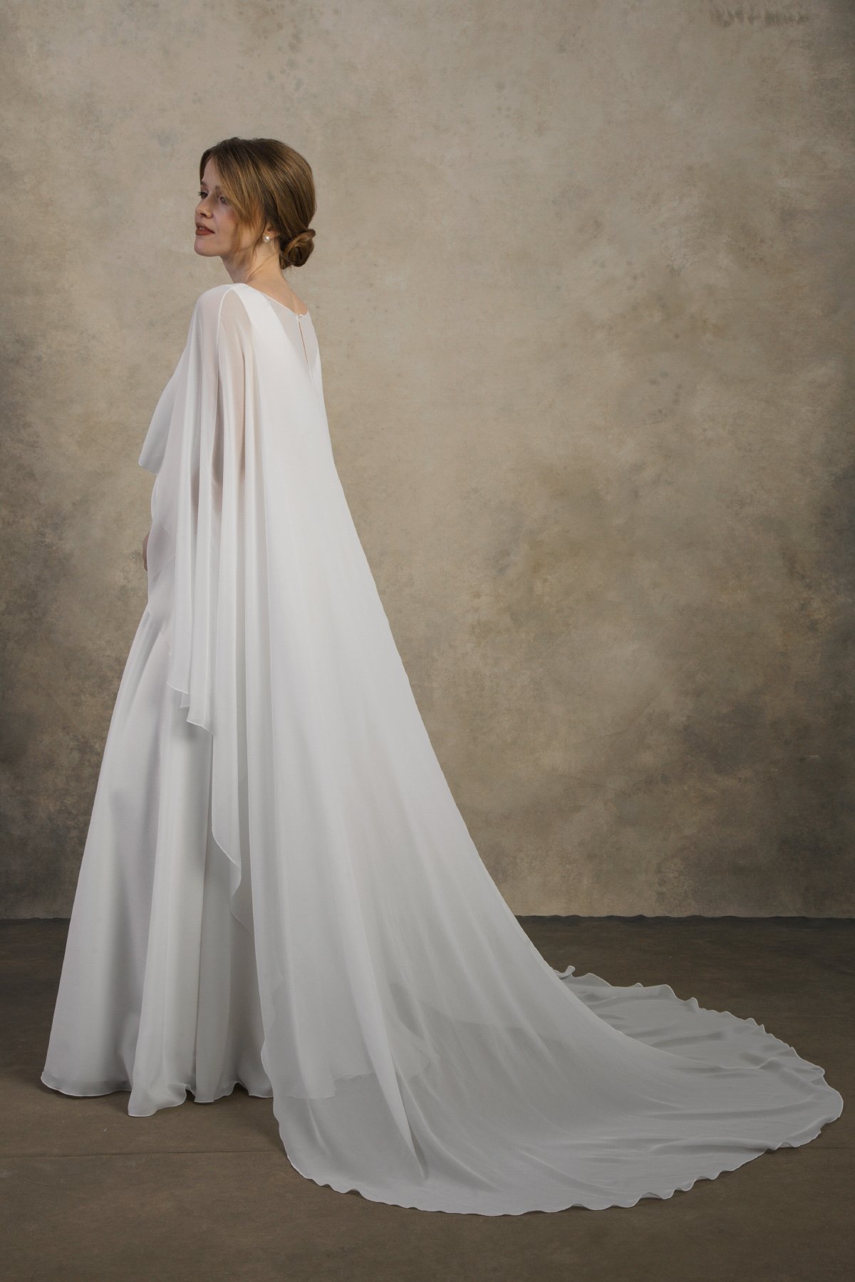 Side view of a maternity gown with a long flowing chiffon cape and extended train.